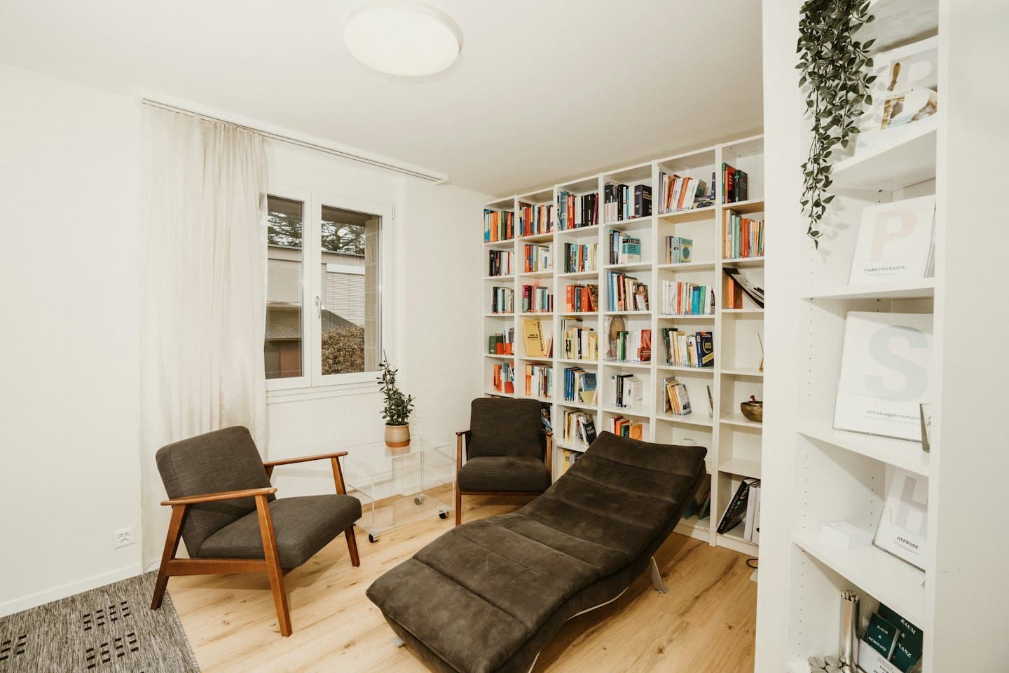 Accogliente studio di terapia con poltrone, chaise longue e librerie.